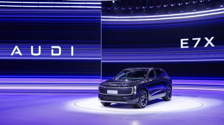 A black Audi E7X on a showing room floor in front of a purple background at the Beijing Auto Show.