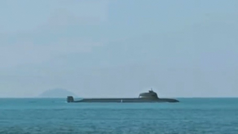 A rare glimpse at a Type 093B nuclear submarine as it surfaces above open waters.