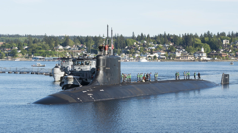 Submariners stand atop a surfaced American Seawolf submarine as it idles in port.