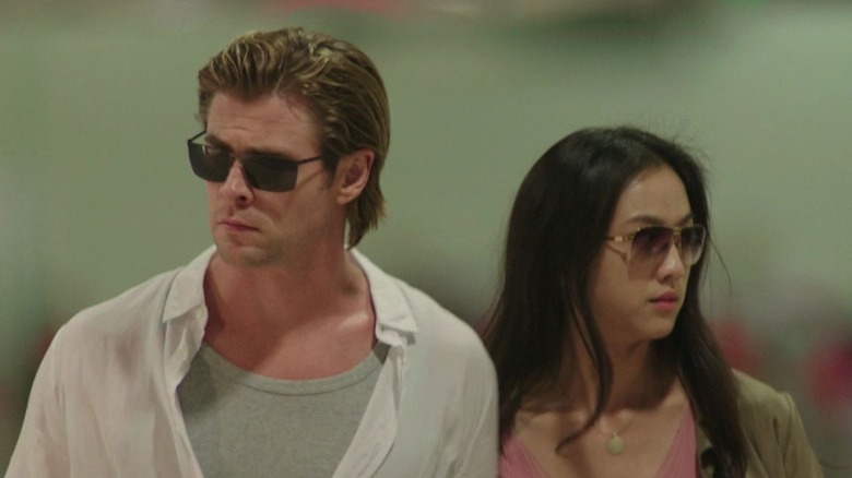 Chris Hemsworth (Nick Hathaway) and Tang Wei (Chen Lien) in Blackhat, standing side by side in sunglasses, looking away from each other