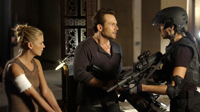 Edward Carnby stands beside Aline Cedrac while speaking to an armed soldier in "Alone in the Dark" (2005).