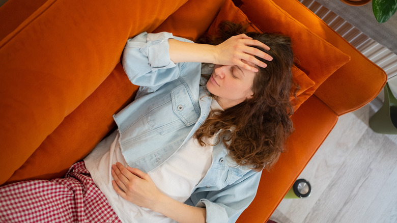 A woman lies on a couch in pain