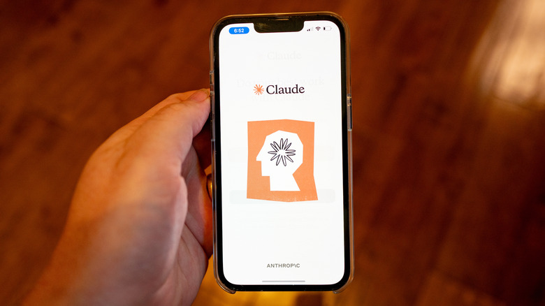 Person holding a smartphone with the Anthropic Claude logo displayed.