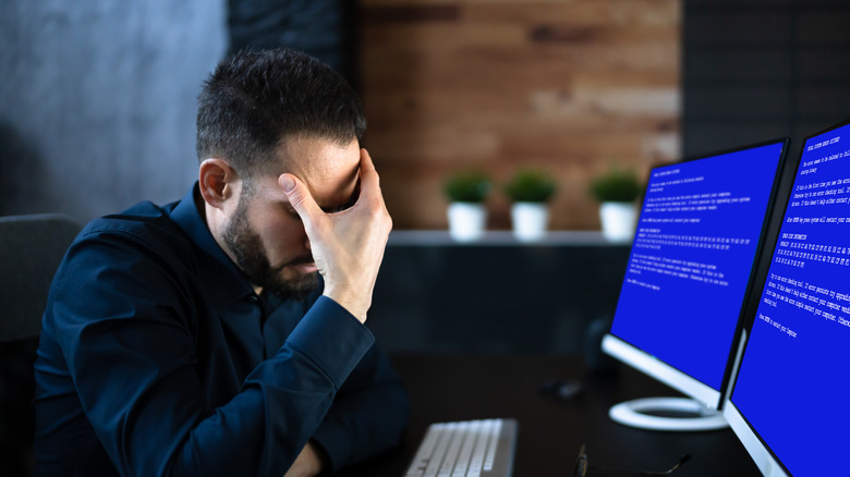 A man reacting in frustration to double blue screens on a computer