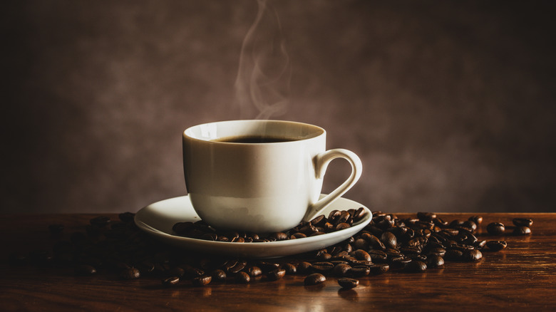 cup of coffee surrounded by coffee beans