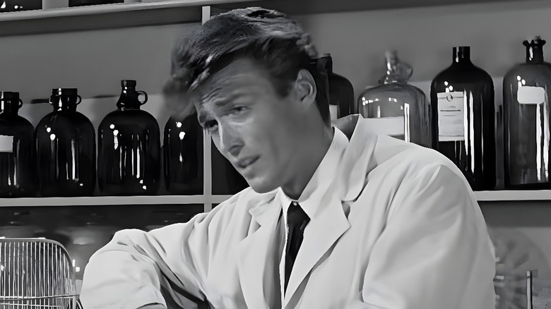Lab technician (Clint Eastwood) standing behind a counter in 