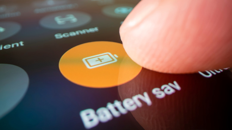 A finger pointing at the Battery Saver option in Quick Settings