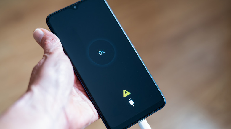 Close-up of phone with zero percent battery displaying on screen