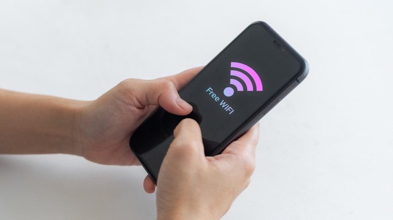 Someone holding a mobile phone with a Free Wi-Fi message on screen.