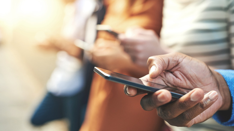 A row of people using their smartphones in public