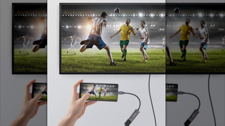 A person watching a soccer match using their phone on a TV