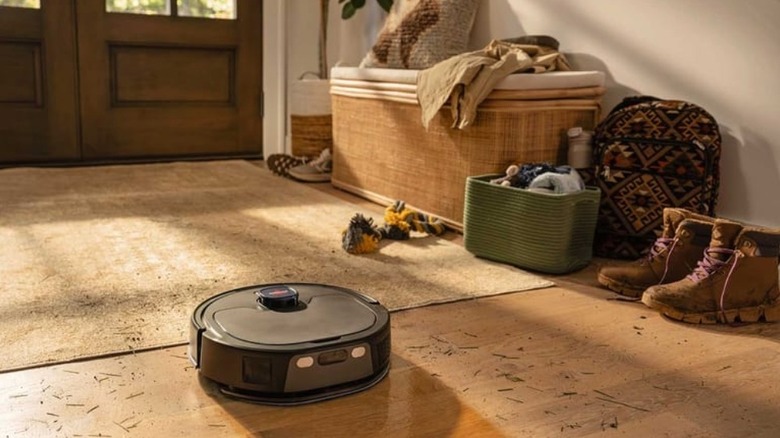 A Bissell FlexClean FurForce robot vacuum-mop cleaning the floor of a dirty entry way