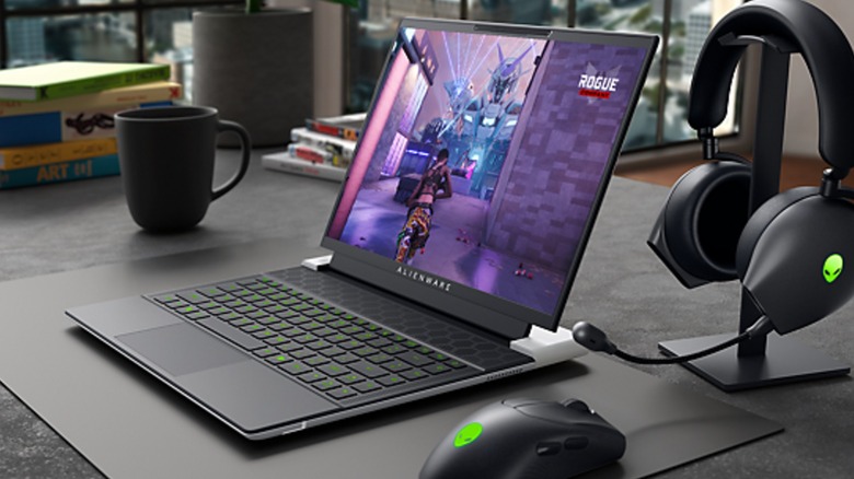 Alienware x14 R2 gaming laptop on a desk next to a mouse, headphones, and a coffee mug