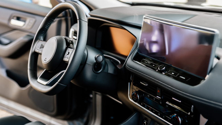 Modern car interior with steering wheel and digital dashboard.
