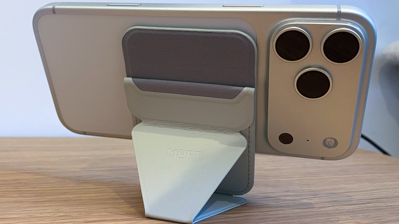 Moft's wallet stand with Find My holding an iPhone 17 Pro Max in landscape mode