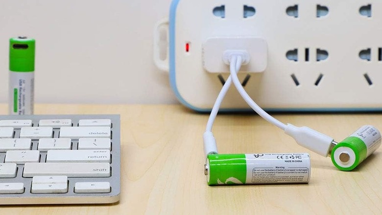 Rechargeable batteries sitting next to a keyboard on a desk being charged