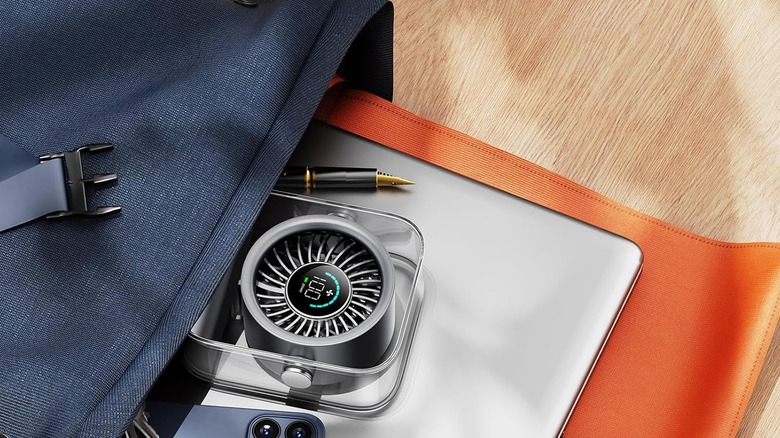 A small rechargeable desk fan sitting in a bag on a desk