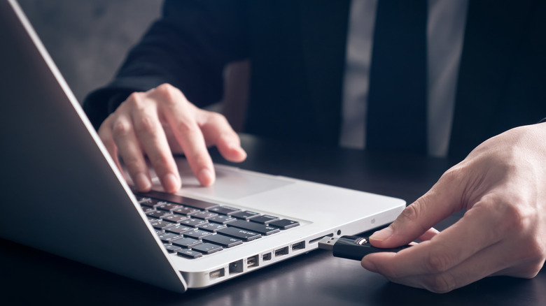 A man pluggin a USB-A device into a laptop
