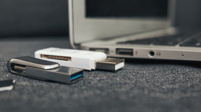 USB thumb drives sitting on a desk next to a laptop