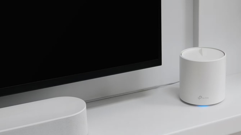 A TP-Link Deco X60 router next to a TV in a home theater setup