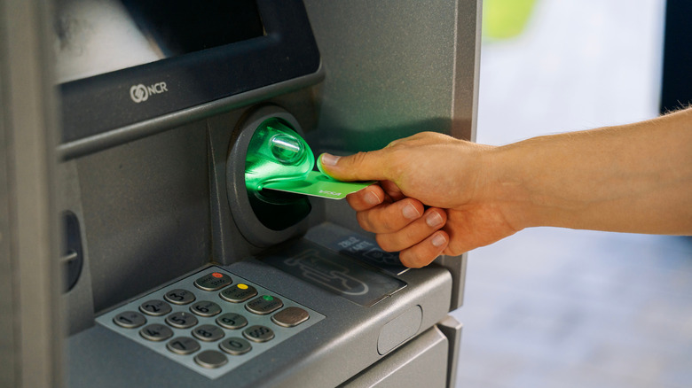 Person inserting a debit card into an ATM