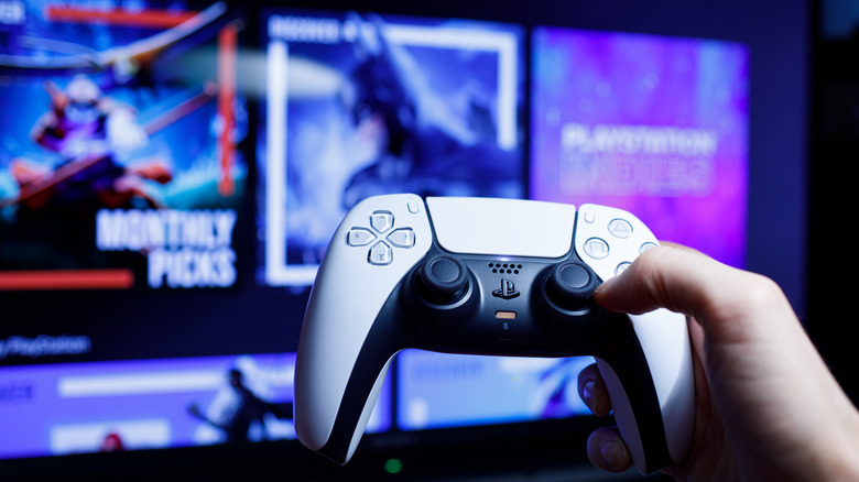 PS5 DualSense controller held up in front of TV with PlayStation Store visible.