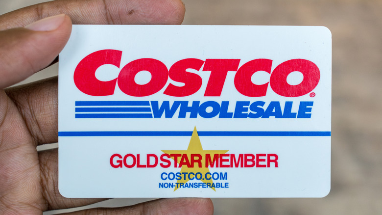 A closeup of a Costco Wholesale Goldstar Membership card being held in a user's left hand
