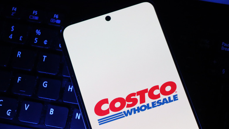 Smartphone with the Costco logo on the screen in front of a keyboard