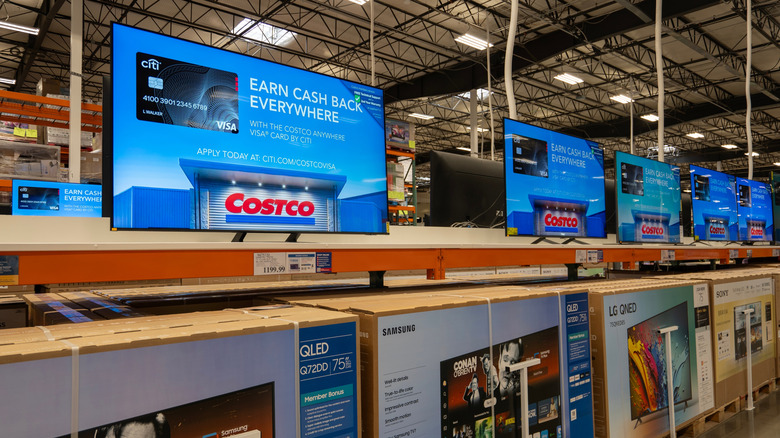 Various TVs side by side with their boxes beneath them in Costco