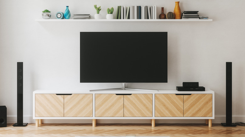 A symmetrical front view of a cozy TV setup with beige and white aesthetics, the TV is turned off