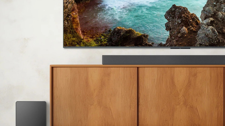A TCL soundbar and subwoofer under a living room TV.