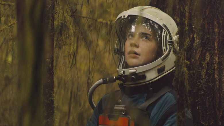 Cee leaning against a tree in full space gear