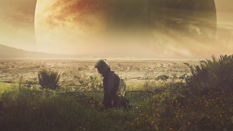 Cee kneeling in the grass in front of a giant planet