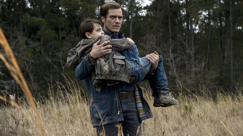 Ray carrying Alton in his hands in a field