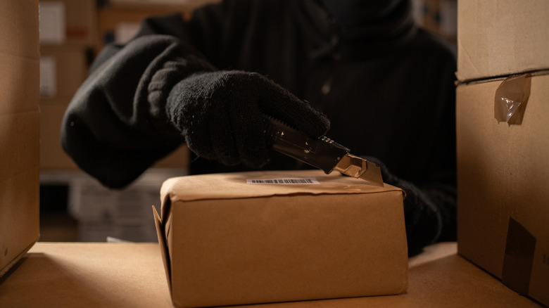 a thief opening a package in a warehouse