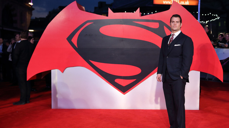 Actor Henry Cavill standing by the Batman vs. Superman logo