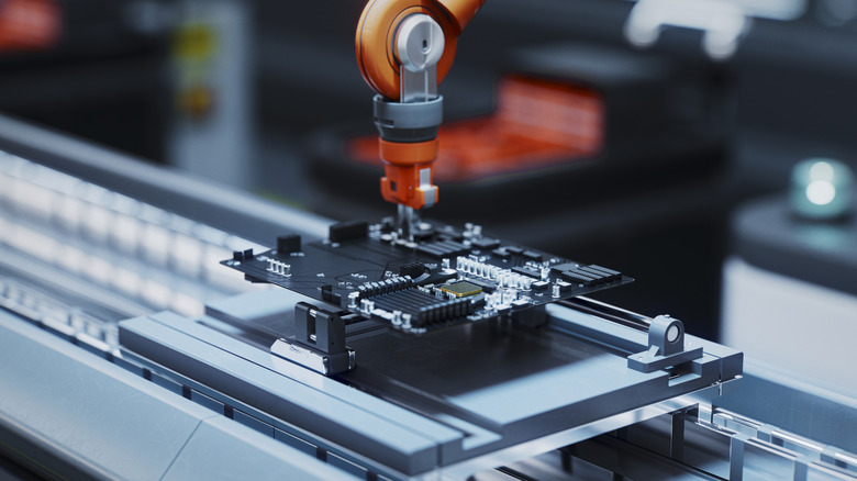 Robotic arm building a motherboard on a manufacturing line