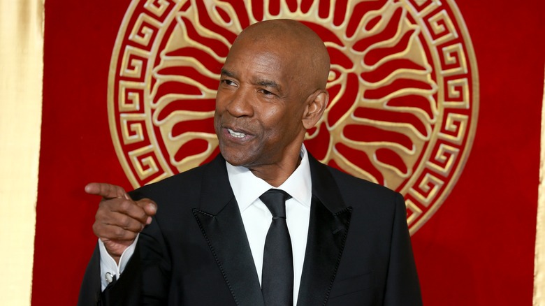 Denzel Washington pointing in front of red and gold background
