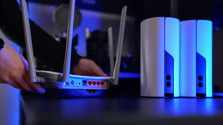 Someone arranging network devices on a table including a traditional router and mesh routers.