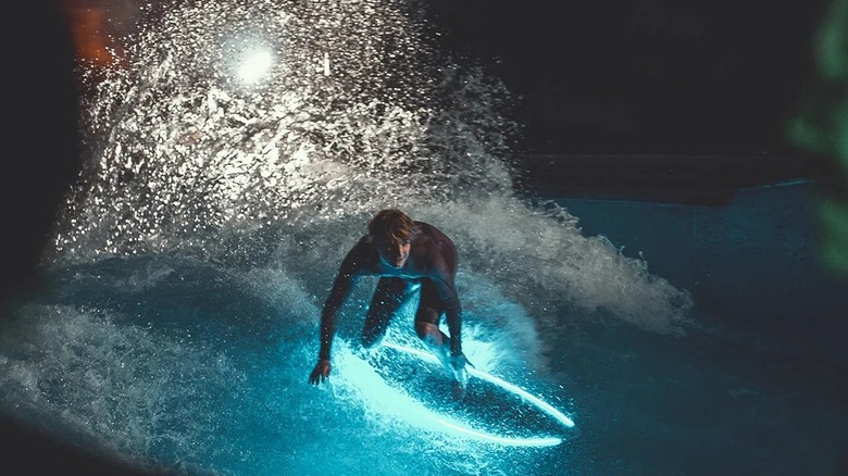 A man riding a surfboard with blue lights around it