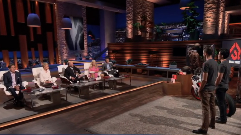 Two men on Shark Tank wearing Brake Free shirts, with the hosts of the show in view