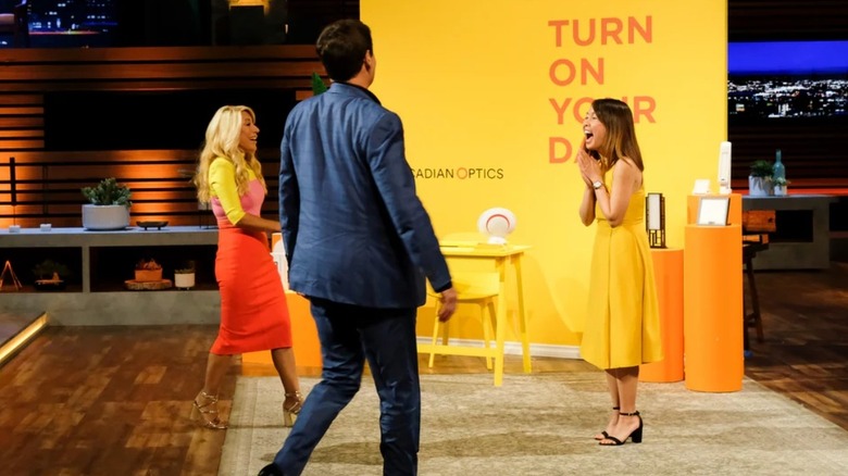 Lori Greiner and Mark Cuban walking up to Circadian Optics founder Amber Leong after making a deal on Shark Tank.