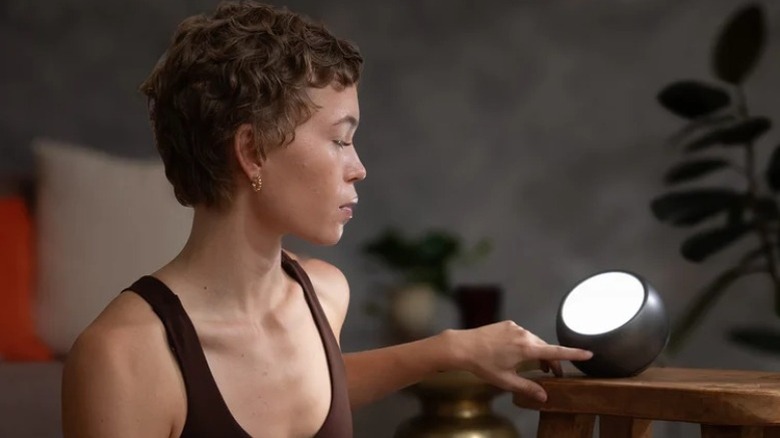 A woman with short hair using a spherical light therapy lamp