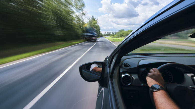 Person driving in a car with the window down.