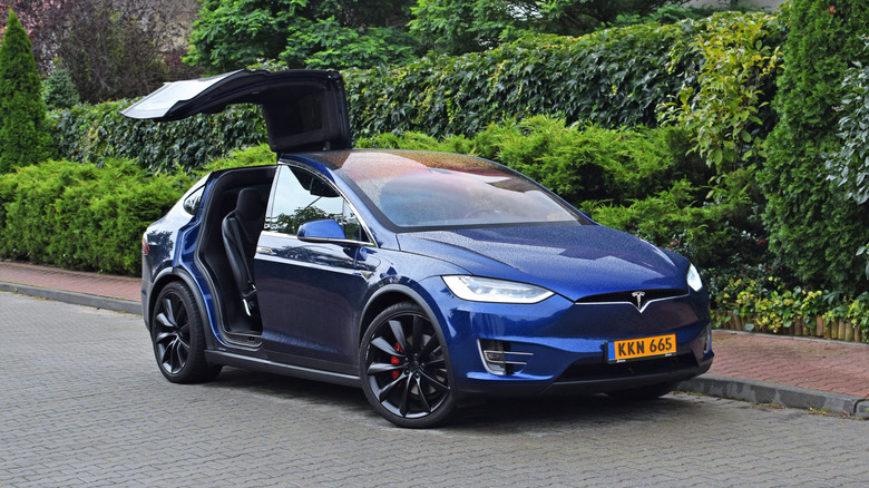 A blue Tesla Model X on a brick road