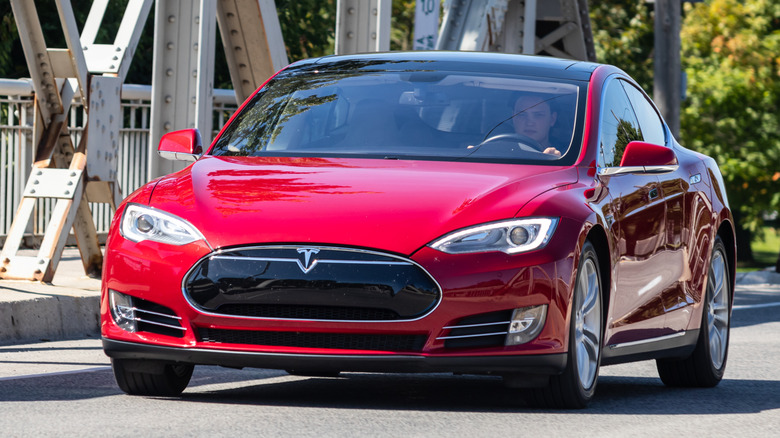 A red Tesla Model S on driving on a bridge