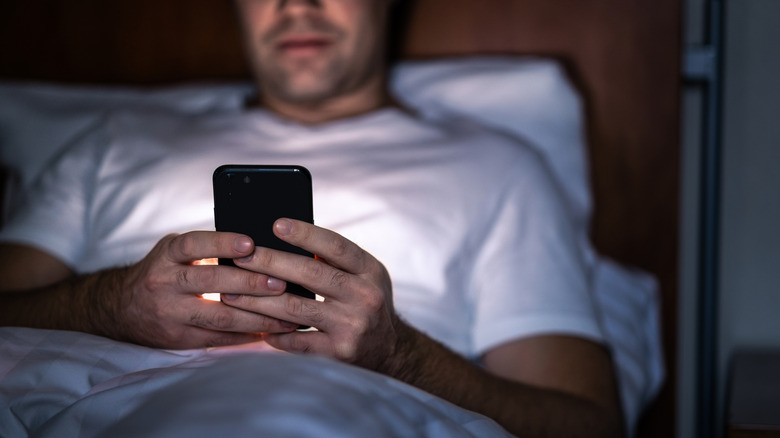 a man looking at his phone at night in bed