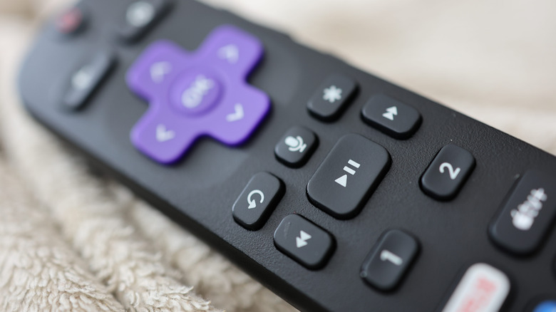 A photograph of a Roku TV remote with bokeh effect applied blurring the top image of the photo.