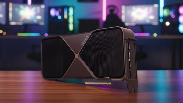 Nvidia RTX 5090 graphics card sitting on a desk in front of a colorful gaming setup.