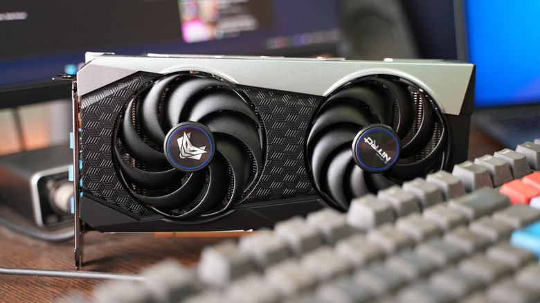AMD Radeon graphics card with dual cooling fans sitting on a desk beside a keyboard.